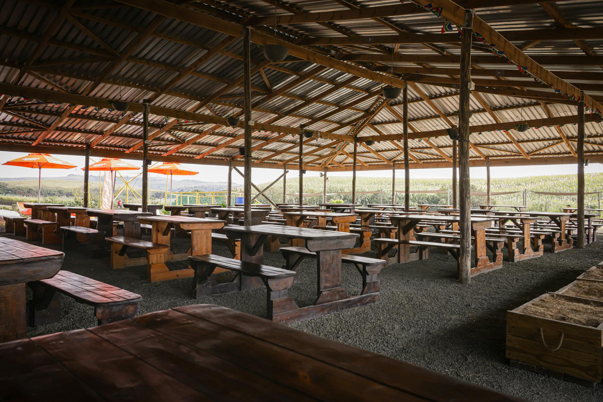 Open-air market seating area with wooden benches and tables under a canopy.